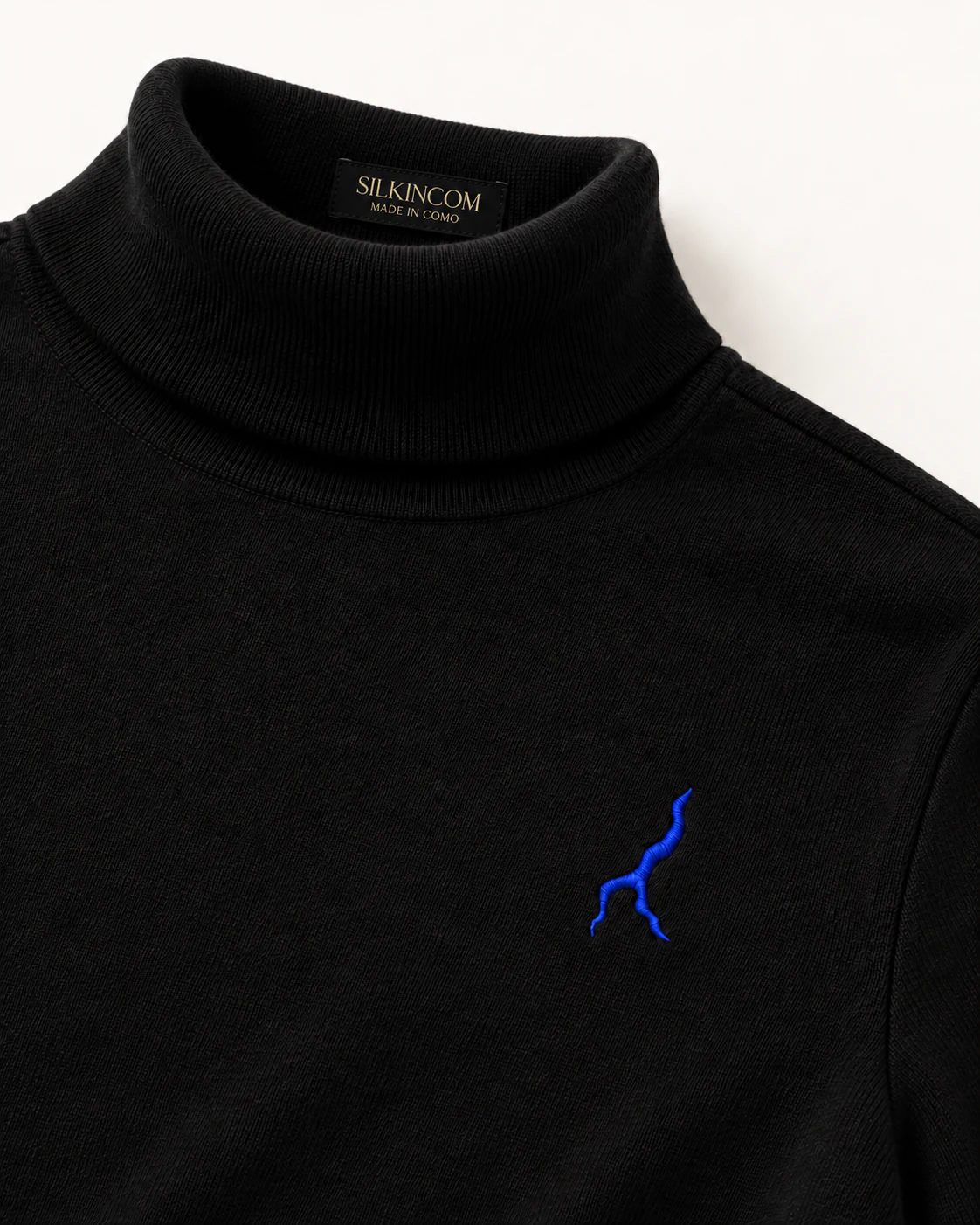 Domaso — Dolcevita in lana merino nera · Il profilo del Lago, ricamato in blu.